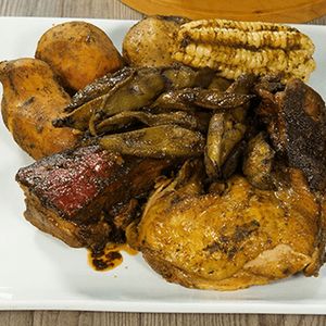 In the image you can see the traditional pachamanca dish, which consists of pieces of meat and chicken with a smoky appearance, and is also accompanied by corn, potatoes and some pods.